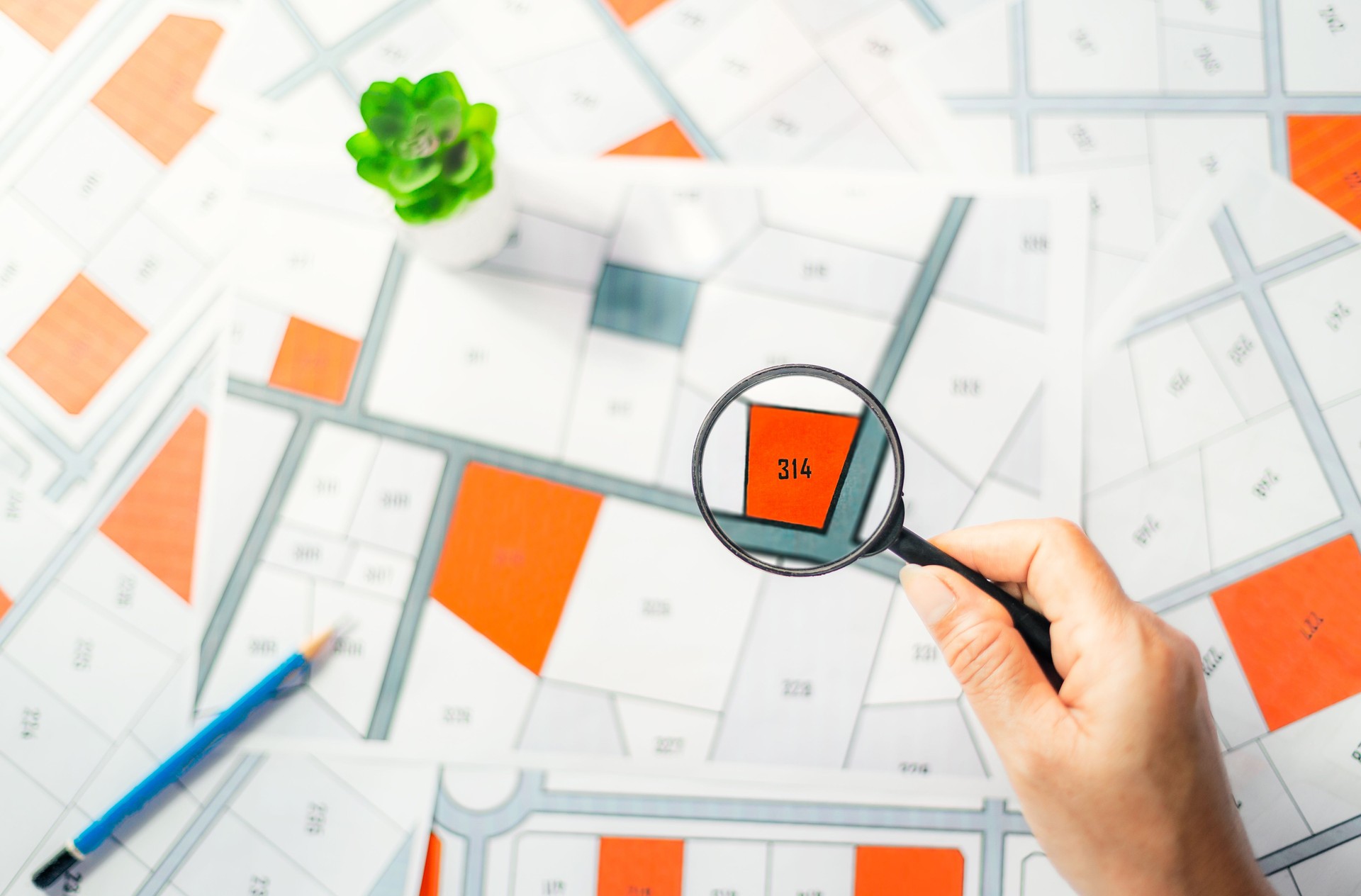 Man holding magnifier on cadastre map search for assesses to buy the land lands. real estate concept with vacant land for building construction and housing subdivision for sale, rent, buy, investment.